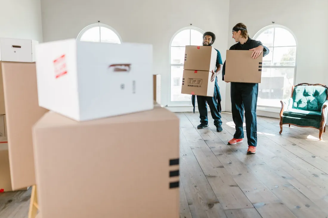 Zwei Umzugshelfer tragen ein Sofa aus einem Hauseingang